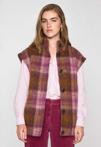 Gilet en laine à carreaux roses, violets et bruns. Manches courtes, col montant et boutons noirs sur le devant. Fini texturé.