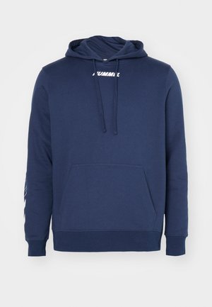 Granatowy polar z kapturem, wykonany z miękkiego materiału, z frontową kieszenią, z białym logo na klatce piersiowej i prostym wzorem.