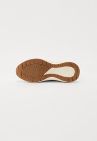 Semelle extérieure de baskets en caoutchouc gomme avec un motif texturé. Présente une semelle intermédiaire blanche et un graphique en forme de cœur. Bords lisses, design courbé.