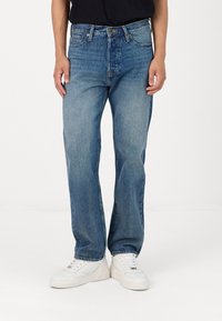 Light blue straight-leg jeans with a faded wash, five pockets, and metal button closure, paired with white sneakers.