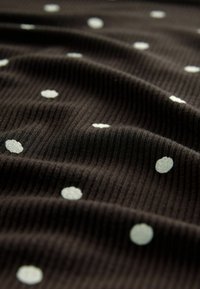 Terie neagră cu nervuri, decorată cu puncte albe dispersate de dimensiuni variate, creând o suprafață texturată cu un model subtil.