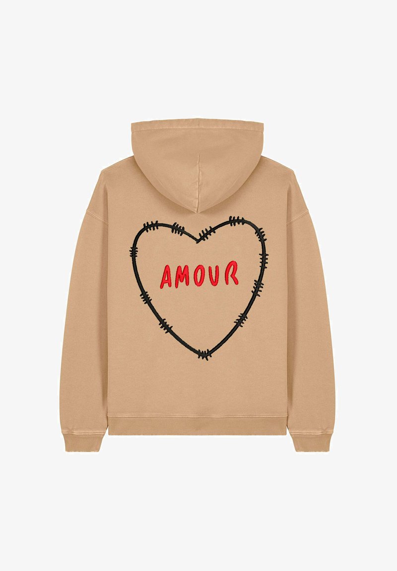 Sweatshirt à capuche beige avec un contour de cœur noir brodé et le texte rouge "AMOUR" au dos. Le matériau semble doux et décontracté.
