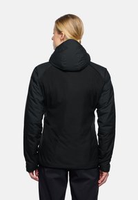 Zwarte pufferjas met capuchon, voorzien van een gladde, matte textuur en contrasterende donkere schouderpanelen. Slank gesneden ontwerp met lange mouwen.