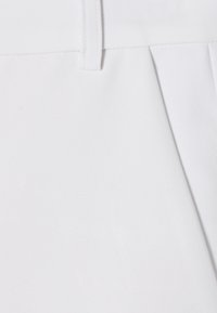 Bílá tkanina s hladkým povrchem a mírným leskem. Obsahuje rovný střih s pasem a sklady na jedné straně.