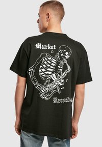 Must must hele musta, millel on valge luustikukujutis, mis mängib saksofoni, ning tekst "Market" ja "Records". Lühikesed varrukad, vabalt istuv.