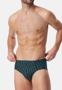 Slip da nuoto verde scuro con righe verticali bianche, realizzato in tessuto elastico. Design aderente con vita a media altezza e copertura minima.