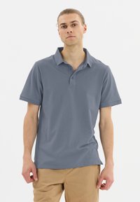 Ljusgrå kortärmad polo-shirt med krage, med en liten logotyp på bröstet och en avslappnad passform. Slät, mjuk tygtextur.