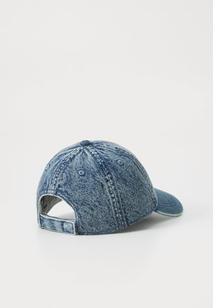 Denim baseball cap with a curved visor, blue color, stitched patterns, and adjustable back strap. Textured fabric with eyelet ventilation holes.