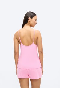 Roosa varrukateta pealiskomplekt koos lühikeste pükstega, valmistatud pehmest materjalist, millel on reguleeritavad rihmad ja lõdvestunud lõige, ideaalne vabaajarõivastuseks.