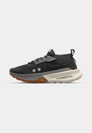 Fekete sportcipő struktúrált felsőrésszel, szürke részletekkel, narancs és fehér talppal, ZoomX párnázottsággal és Vibram díszítéssel.