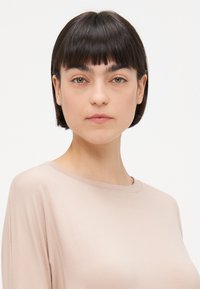 Svijetloružičasti, dugih rukava, top s okruglim izrezom, glatke teksture i elegantnog pada. Ima jednostavan, minimalistički dizajn bez uzoraka.