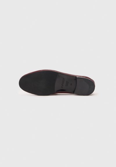 Burgundy leather shoe sole with ribbed black rubber bottom, featuring embossed brand name and model details for traction and durability.