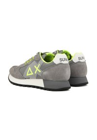 Sneaker in suede grigio con accenti neon, dotate di una suola nera e una linguetta bianca sul tallone. Il design include un dettaglio logo geometrico sul lato.