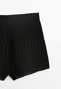 Shorts en crochet noirs avec un design texturé, composée d'une partie supérieure unie et d'un bas délicatement orné d'un motif intricate.