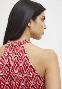 Top con collo all'americana in un vivace motivo rosa e rosso, con schiena a chiave e dettaglio di bottone decorativo. Tessuto liscio e leggero.
