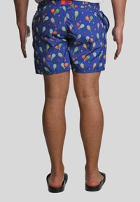 Pantaloni da bagno blu con un motivo giocoso di racchette da tennis e palline colorate. Realizzati in materiale leggero con vita elastica.