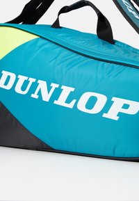 Dunlop Reisetasche in Blaugrün und Schwarz, mit einem leuchtend grünen Akzent, aus strapazierfähigem Material, mit einem oberen Reißverschluss und einem auffälligen weißen Logo.