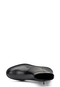 Botín de piel negra con textura suave, punta redonda y cremallera lateral para facilitar el uso. Diseño minimalista con costuras sutiles.