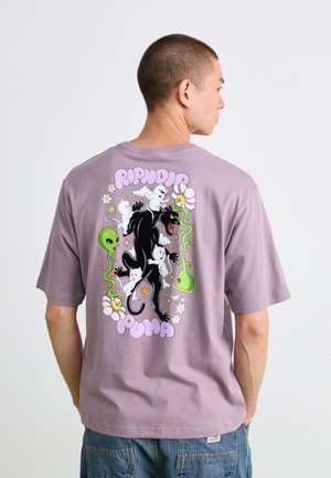 Man wearing purple t-shirt with colorful graphic of black panther, white cats, green aliens, flowers, and "Ripndip Puma" text on the back.