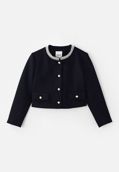 Fekete, rövidített kabát hosszú ujjakkal, díszített gallérral, amelyen átlátszó és arany díszek találhatók, valamint arany gombokkal az elején és a zsebeken.