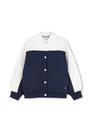 Blouson bomber blanc et bleu marine à boutons, manches longues, avec poignets, col et bas en côte.