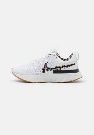 Weißer Sportschuh mit strukturiertem Profil, Leopardenmuster-Nike-Swoosh und Innensohle, Schnürdesign und Zuglasche an der Ferse.