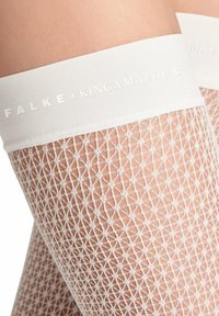 Calze autoreggenti bianche a rete con un bordo bianco solido che presenta un marchio in rilievo. Il materiale è strutturato con un motivo a diamante.