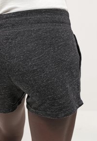 Grå sportshorts i texturerat tyg med enkel design och bekväm midjeresår, med synliga sidofickor.