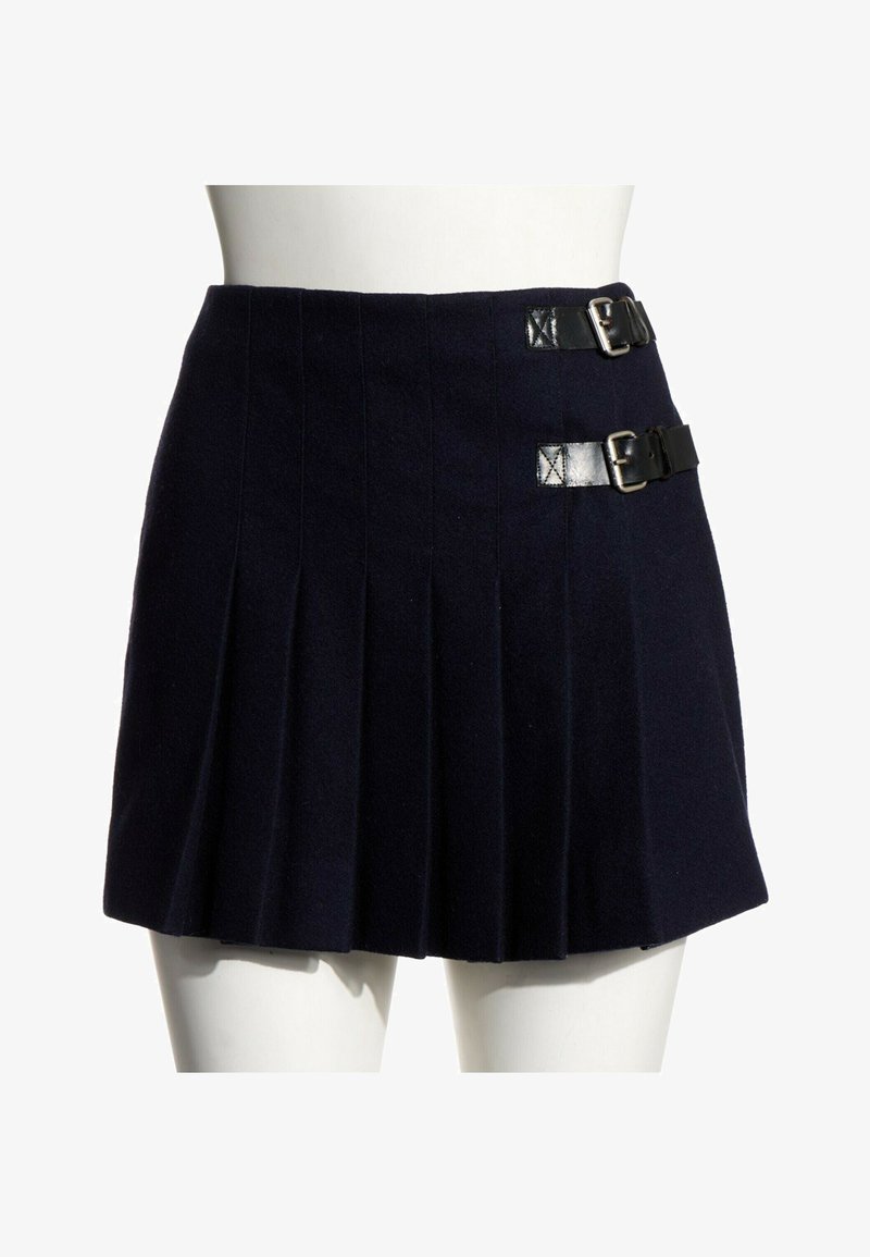 Mini-jupe plissée noire avec deux bretelles en cuir à boucle sur le côté droit, présentée sur une taille et des cuisses supérieures de mannequin blanc.