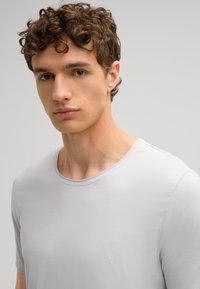 Lichtgrijs T-shirt met korte mouwen van zacht materiaal, met een ronde halslijn, gladde textuur en minimale stikseldetails.