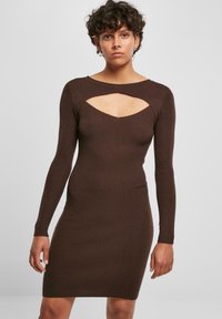 Abito in maglia a coste marrone con maniche lunghe, ritaglio strutturato sul petto, linea aderente e design minimalista.