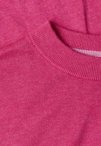Gros plan d'un tissu tricoté rose vif avec un col rond côtelé montrant la texture du tricot et les détails fins du fil.