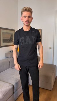 T-shirt nera con lettering "GAP" in rilievo e audace sulla parte anteriore; abbinata a pantaloni neri. Tessuto semplice, vestibilità casual.