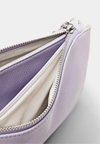Levandulová kožená taštička se stříbrným zipem, obsahující dvě vnitřní přihrádky s krémovou látkovou podšívkou a texturovaným povrchem.