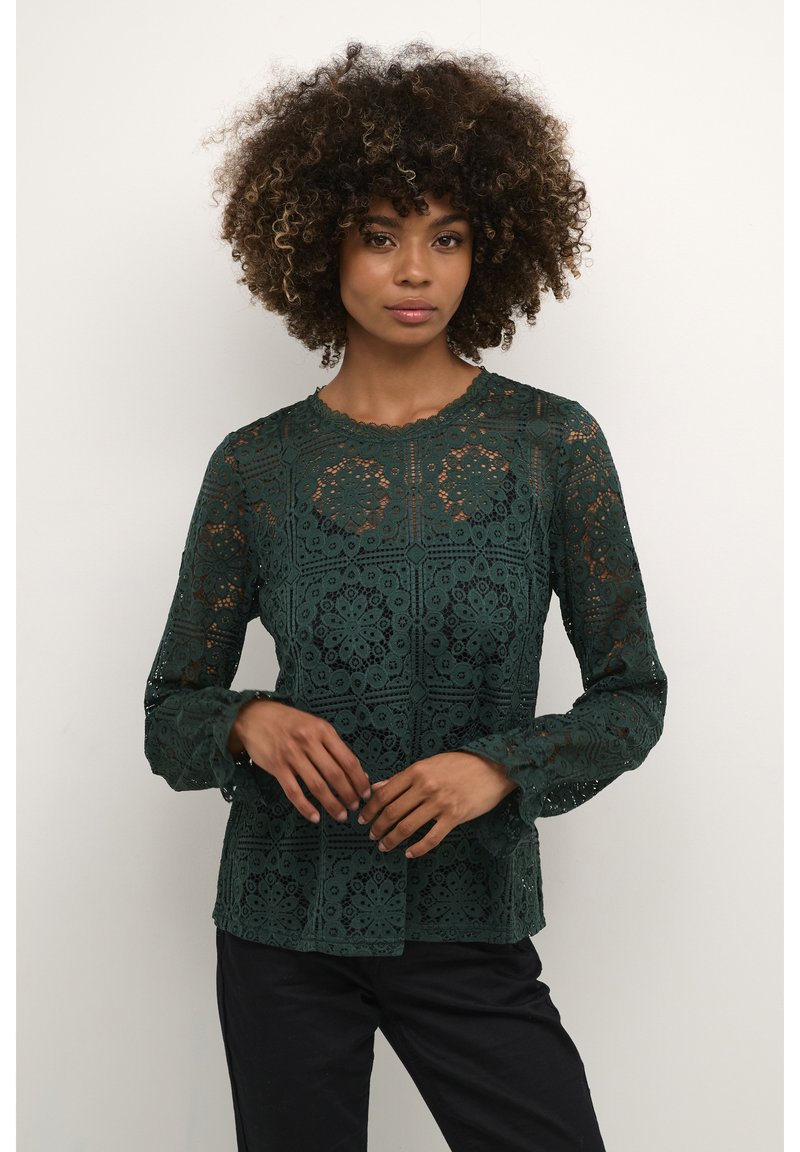 Top in pizzo verde scuro con intricati motivi floreali, maniche lunghe e scollatura a onda. Materiale leggero con una finitura testurizzata.