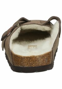 Zapato de ante marrón sin cordones con suela de corcho, forro blanco suave y una correa de acento marrón. Con punta redondeada y un diseño cómodo y casual.