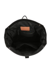 Svart handbag i canvas med rundad form. Insidan har en beige läderetikett och en ficka med dragkedja för säker förvaring.