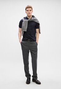 Πολυτελής ναυτικό μπλουζάκι polo σε στενή γραμμή, γκρι πουλόβερ ριγμένο στους ώμους, γκρι παντελόνι, μαύρη ζώνη, μαύρα loafers. Λείος ύφασμα και κομψός σχεδιασμός.