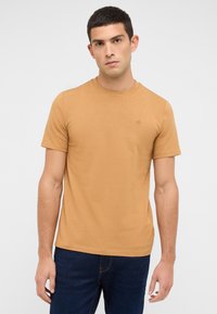 Koszulka z krótkim rękawem i okrągłym dekoltem w jednolitym jasno-brązowym kolorze. Wykonana z bawełny o gładkiej fakturze. Małe logo na piersi.