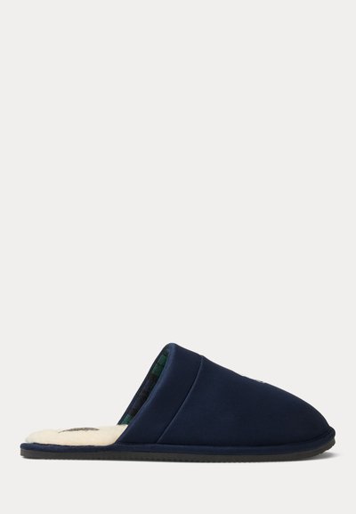 Παντόφλα από σουέντ σε ναυτικό μπλε με μαλακή κρέμ επένδυση, χωρίς πίσω μέρος, με πράσινο καρό σχέδιο στο εσωτερικό και υφασμένο μαύρο πέλμα.