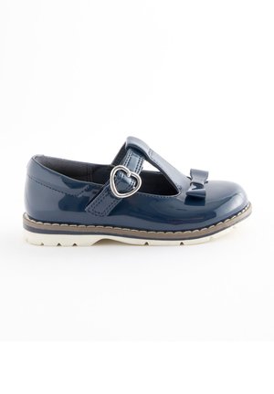 Zapato Mary Jane de charol azul marino para niña, con hebilla en forma de corazón, detalle de lazo y suela blanca, mostrado de perfil.
