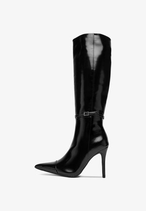 Černé lakované kozačky po kolena s špičatou špičkou, vysokým jehlovým podpatkem a ozdobným páskem kolem kotníku.