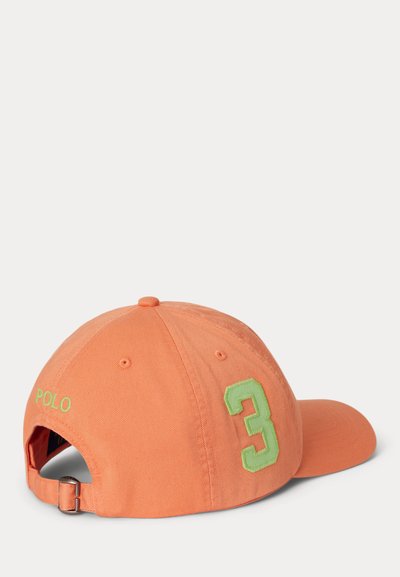 Gorra de béisbol naranja con el número verde "3" en el lateral y "POLO" bordado en verde cerca de la correa ajustable en la parte trasera.