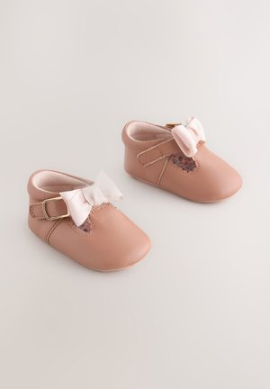 Chaussures pour bébé en cuir rose avec une texture douce, un nœud décoratif à l'avant et une bride à boucle. Présentent une ouverture sur le côté.
