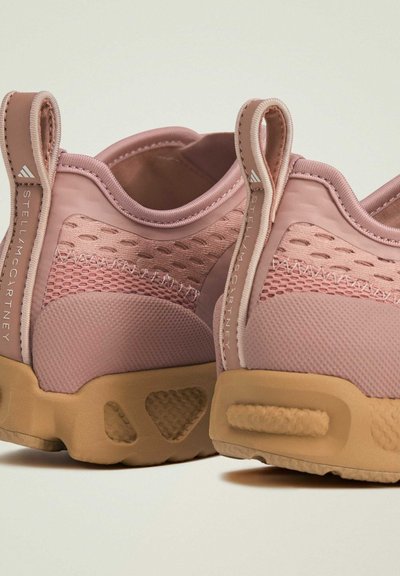 Rose pink athletic shoes with a textured mesh upper, padded collar, and a light brown rubber sole featuring triangular cutouts.