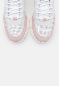 Baskets blanches et gris clair avec des accents en daim rose, tige perforée, lacets plats blancs et semelle épaisse.