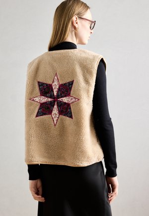 Beige fleece vest featuring an embroidered star design in pink, black, and floral patterns on the back. Round neckline and sleeveless cut.