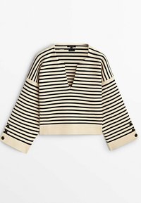Pull en maille à rayures horizontales crème et noir, manches longues larges, col en V profond et détails de boutons sur les poignets.
