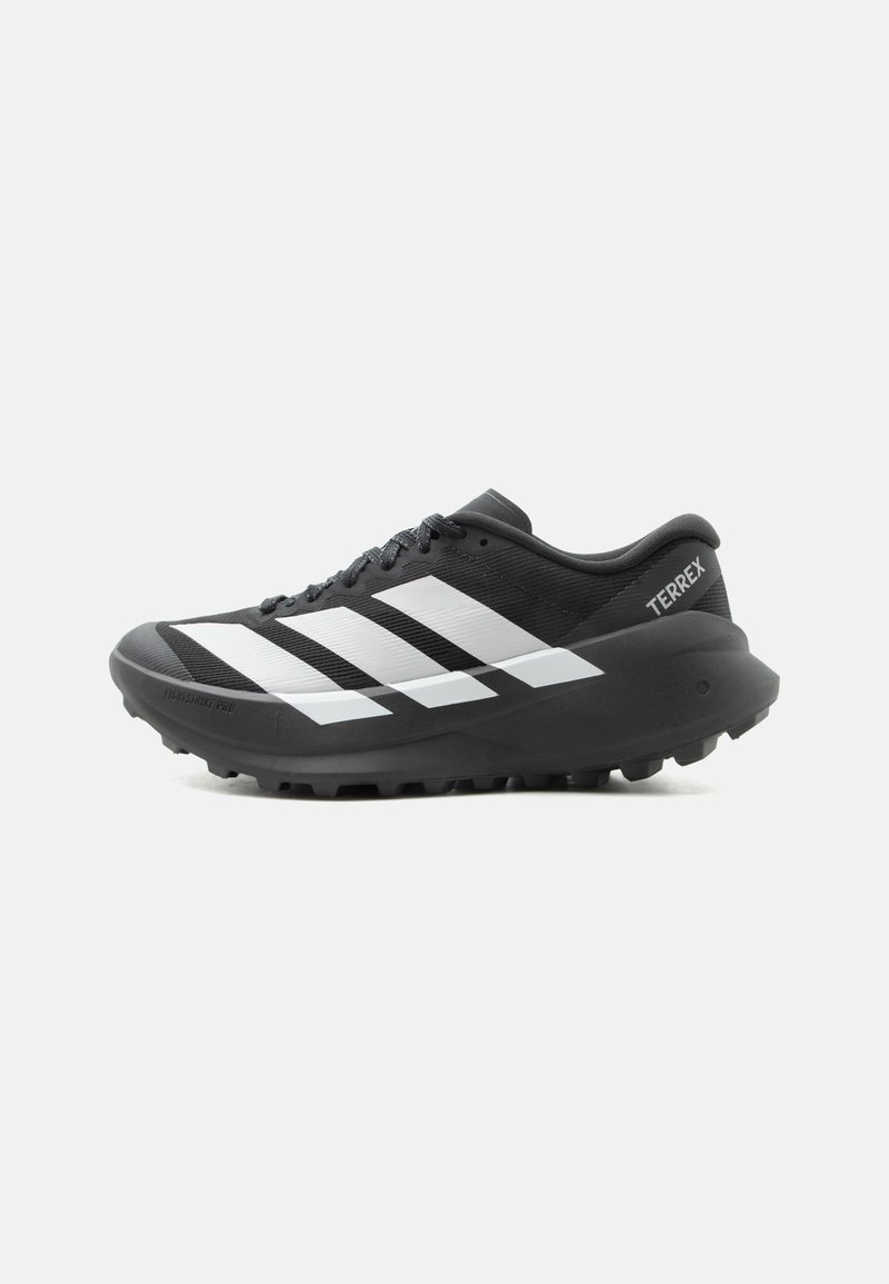 Μαύρο-άσπρο παπούτσι trail running Adidas Terrex με κορδόνια, ανθεκτική σόλα και τρεις λευκές διαγώνιες ρίγες στο πλάι.