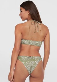 Conjunto de bikini verde oliva con un diseño estampado. La parte superior es de estilo bandeau con un lazo en el cuello y la parte inferior tiene un corte de tiro bajo.
